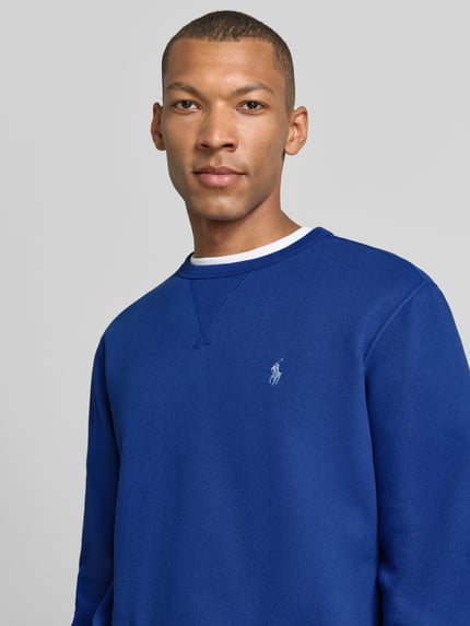 Männermodel trägt Regular Fit Sweatshirt aus Baumwoll-Mix von Polo Ralph Lauren in kräftigem Blau mit glatter Struktur, Nahaufnahme Oberkörper. Herren Sweatshirt von Polo Ralph Lauren