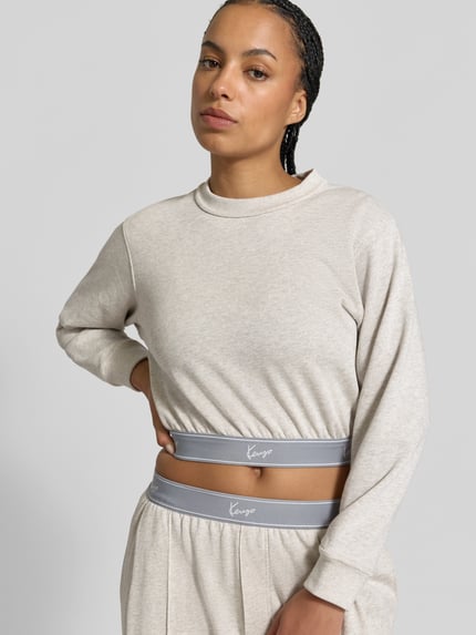 Vrouwenmodel draagt Cropped Sweatshirt met Logo-Stitching van Kenzo in lichtbeige, puur katoen, korte fit, ronde hals, elastische boorden, ruglengte maat S 44 cm, Nahaufnahme bovenlichaam.