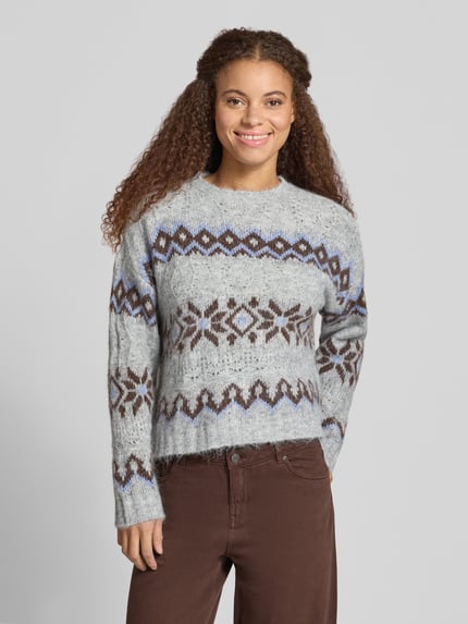 Frauenmodel trägt Pullover mit Effektgarn-Details Modell 'ONLSTOCKHOLM' von ONLY in mehrfarbiger Strickoptik, geometrisches Melange-Muster, lange Ärmel, gerippte Abschlüsse, Ganzkörperansicht von vorne.