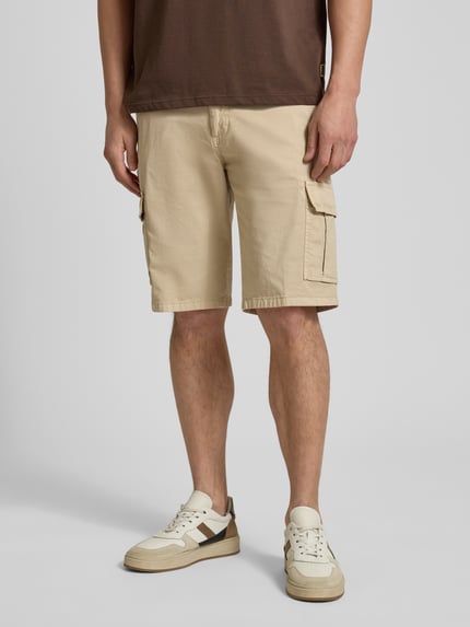 Männermodel trägt Bermudas mit Cargotaschen von bugatti in Beige, Regular Fit, Knopf- und Reißverschluss, Ganzkörperansicht von vorne.