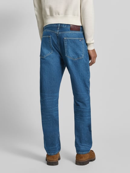Männermodel trägt Regular Fit Jeans aus reiner Baumwolle von Tommy Hilfiger, Optik: Unifarben, Denim, Label-Patch, 5-Pocket-Design, Ganzkörperansicht Rückansicht.