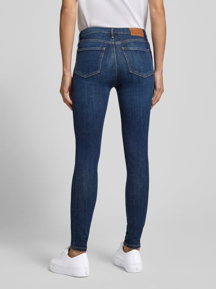 Vrouwenmodel draagt Skinny Fit Jeans im 5-Pocket-Design Modell 'COMO' van Tommy Hilfiger Sportswear in blauw katoenmix met stretch, labeldetail, knoop- en ritssluiting, bandwijdte 36 cm, binnenbeenlengte 69 cm, volledige lichaamsweergave achteraan.