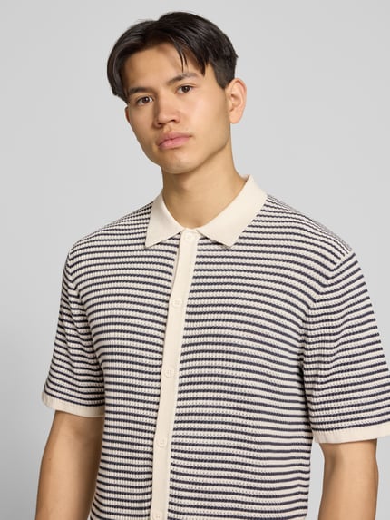 Mannelijk model draagt Regular Fit vrijetijdsoverhemd met 1/2-mouwen van Jack & Jones van puur katoen, polokraag, knoopsluiting, ruglengte 67 cm, schouderbreedte 58 cm, mouwlengte 28 cm, beige en donkerblauw gestreept, textuur met reliëf, nahaufnahme bovenlichaam.