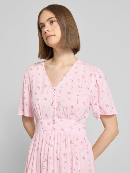 Vrouwenmodel draagt A-lijn midijurk van pure viscose, model 'TALA' van Pieces met allover-print in lichtroze, Nahaufnahme bovenlichaam.