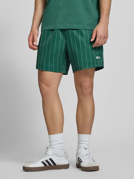 Männermodel trägt Shorts mit Streifenmuster und elastischem Bund von BLKVIS in Grün mit Label-Stitching, Regular-Fit, Ganzkörperansicht von vorne.