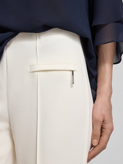 Frauenmodel trägt Slim Fit Stoffhose mit Leistentaschen von Vera Mont, Cremefarbe, elastischer Material-Mix, Nahaufnahme Oberkörper.