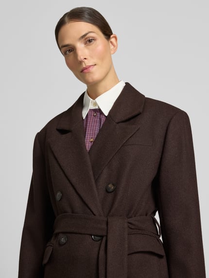 Frauenmodel trägt Mantel mit Bindegürtel Modell 'venja' von Gestuz, brauner Woll-Material-Mix, Zweireiher, Nahaufnahme Oberkörper.