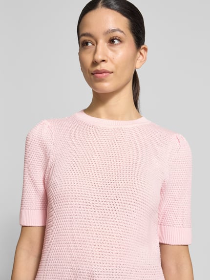 Frauenmodel trägt Slim Fit T-Shirt in Strick-Optik Modell 'Vidalo' von Vila in hellrosa, Baumwolle, Rundhalsausschnitt, Nahaufnahme Oberkörper.