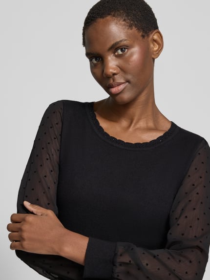 Modelka nosi Regular Fit Strickpullover aus Viskose-Mix Modell 'Fr44anziska' od ZABAIONE, czarny, przezroczyste rękawy z kropkami, muszlowy brzeg, dżety, krój regular fit, długość tyłu S: 55 cm, długość rękawa S: 60 cm, zbliżenie górnej części ciała.