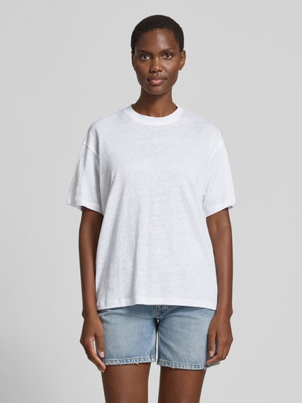 Kobiece modelka nosi damski t-shirt Regular Fit T-Shirt aus reinen Leinen od Anine Bing z lnu, okrągły dekolt, wyhaftowane logo, krótki rękaw, długość tyłu w rozmiarze S: 63 cm, jasny, jednolity kolor, gładka faktura, widok całej sylwetki z przodu.