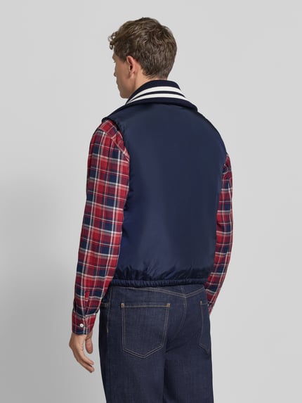 Männermodel trägt Weste mit Kontraststreifen von Dsquared2, marineblau, Umlegekragen in Ripp-Optik, elastischer Bund, Ganzkörperansicht Rückansicht. Gerade Passform, Zweiwege-Reißverschluss, klassische Herrenmode.