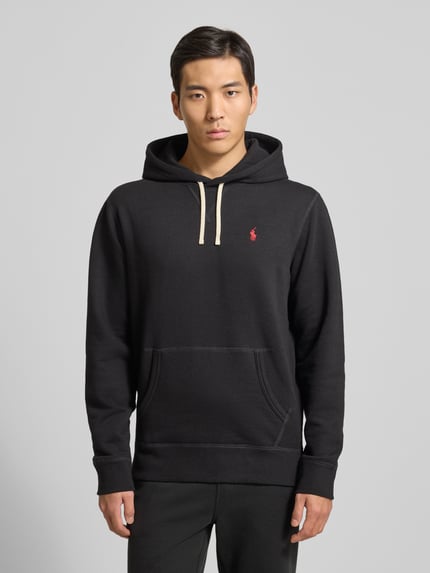 Mannenmodel draagt Hoodie met Label-Stitching van Polo Ralph Lauren in zwart katoenmix met capuchon, tunnelkoord, kangoeroezak, ribboorden, los model, labelstitching, ruglengte maat M 69 cm, mouwlengte 64 cm. Ganzkörperansicht von vorne.