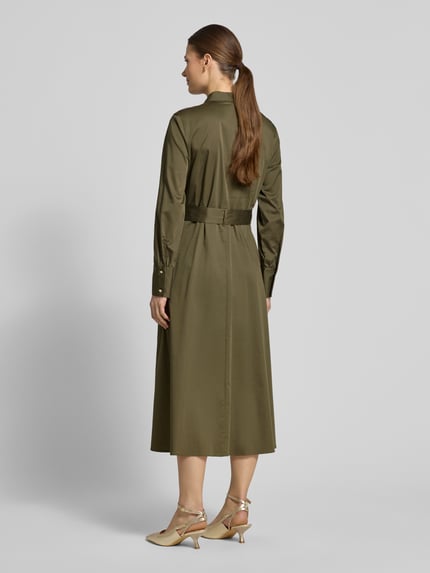 Vrouwenmodel draagt Regular Fit Midikleid mit Umlegekragen van comma, elastische katoenmix in olijfgroen, afneembare stoffen riem, lange mouwen, knoopsluiting, getailleerde regular fit, ruglengte 120 cm, borstwijdte 45 cm, mouwlengte 62 cm. Volledige lichaamsweergave achteraan.