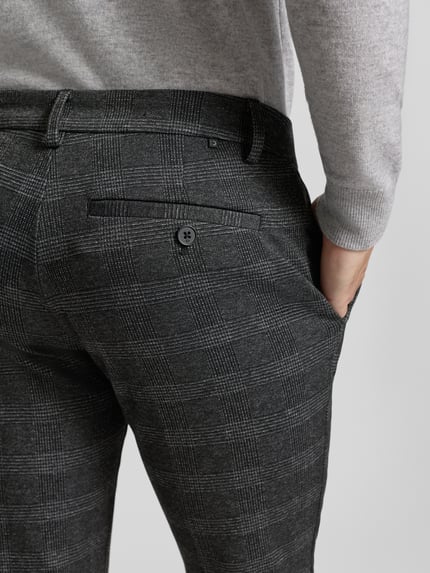 Mannelijk model draagt Slim Fit Chino met Viskose-Anteil van Tom Tailor Denim met all-over ruitpatroon, detailopname rug.