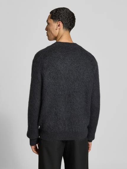Männermodel trägt Regular Fit Pullover mit V-Ausschnitt von ANNARR, dunkle Strick-Optik, gerippte Abschlüsse, Ganzkörperansicht Rückansicht.