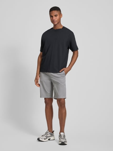 Mannelijk model draagt Tapered Chinoshorts uit katoenmix van BOSS Orange, effen kleuren, tapered fit, labelpatch, 5-pocketmodel, boord elastisch met tunnelkoord, knoop- en ritssluiting, materiaalverwerking twill, Ganzkörperansicht von voren.