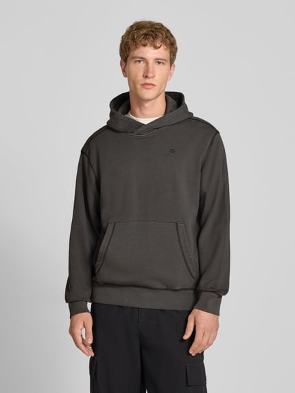 Männermodel trägt Regular Fit Hoodie aus reiner Baumwolle von G-Star RAW in Dunkelgrau, Kängurutasche, einfache Textur, Ganzkörperansicht von vorne.