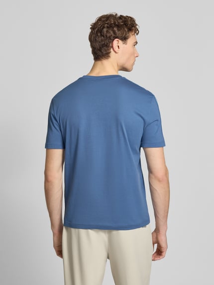 Männermodel trägt T-Shirt mit Label-Patch und Rundhalsausschnitt von EA7 Emporio Armani in Blau, körpernaher Schnitt, Ganzkörperansicht Rückansicht.
