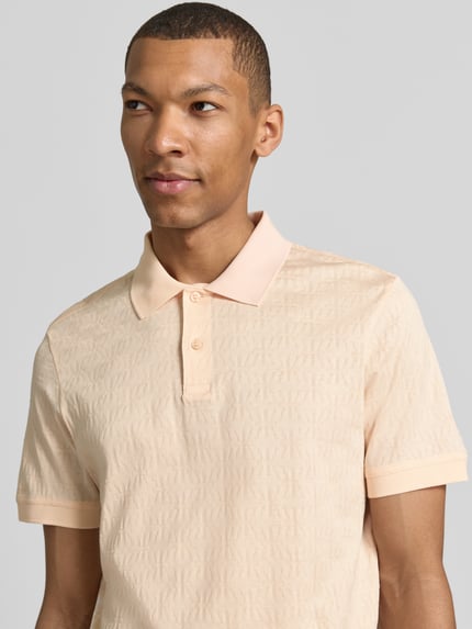 Mężczyznamodel nosi Modern Fit Poloshirt mit Strukturmuster Modell 'Roberto' von JOOP! Collection, bawełna, polokragen, krótka plisa, detal z logo, wzór strukturalny, kolor jasny beż, widok na górną część ciała z przodu.
