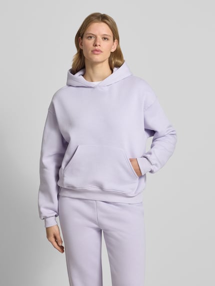 Frauenmodel trägt Hoodie mit Känguru-Tasche Modell 'Iconic' von Gina Tricot in Flieder, Baumwoll-Mix, Relaxed-Fit, Ganzkörperansicht von vorne.