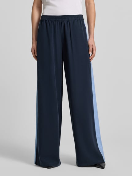 Frauenmodel trägt Fließende Viskose-Hose mit Kontraststreifen - curated by Tinvcb von SIC, Dunkelblau mit hellblauen Seitenstreifen, weites Bein, elastischer Bund, Gesäßtaschen, Ganzkörperansicht von vorne.