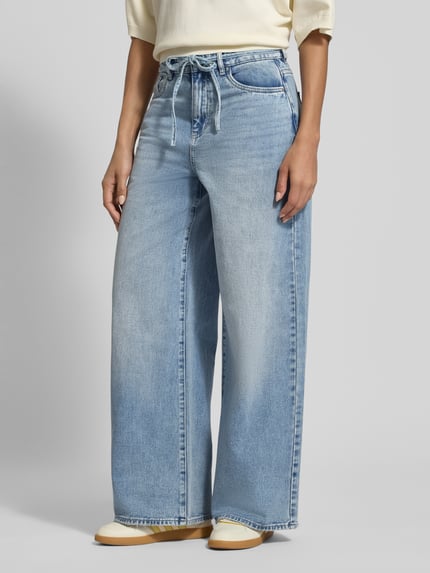 Frauenmodel trägt Loose Fit Jeans aus Baumwoll-Mix Modell 'WIEN' von Vero Moda in Denim-Optik, Bindegürtel, 5-Pocket-Design, Ganzkörperansicht von vorne.