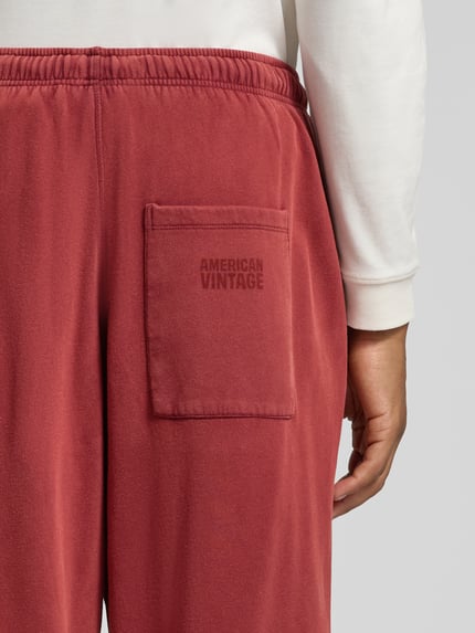 Männermodel trägt Sweatpants mit elastischem Bund Modell 'JITBAY' von American Vintage in Rot, entspannte Passform, Detailaufnahme Rückansicht. Reine Baumwolle, sichtbare Gesäßtasche, dezente Markenprägung.