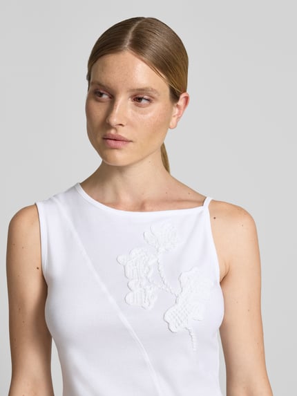Frauenmodel trägt Regular Fit Top aus reiner Baumwolle Modell 'BAGAGLI' von MAX&Co., weiß, florale Stickerei, Nahaufnahme Oberkörper.