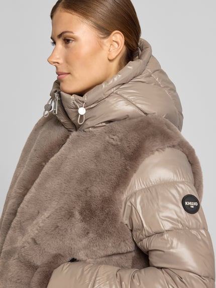 Frauenmodel trägt Steppjacke mit Kunstfell-Besatz Modell 'ONIKA' von khujo in Beige, glänzende Oberfläche, Nahaufnahme Oberkörper. Regular Fit, Kapuze mit Tunnelzug.