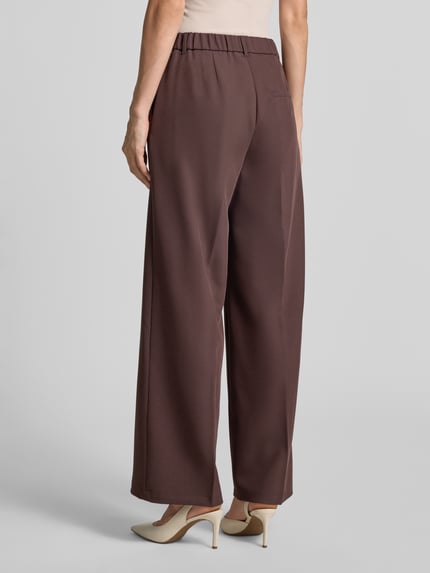 Frauenmodel trägt Regular Fit Anzughose mit Viskose-Anteil von s.Oliver BLACK LABEL in Braun, lockerer Schnitt, glatte Textur, Ganzkörperansicht Rückansicht.