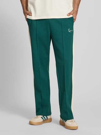 Männermodel trägt Straight Fit Sweatpants mit Logo-Stitching von KARL KANI in Grün und Beige, Elastischer-Material-Mix, Ganzkörperansicht von vorne.