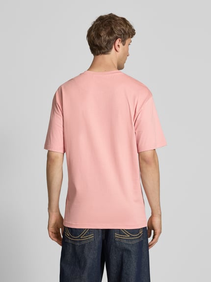 Männermodel trägt Regular Fit T-Shirt mit Logo-Stitching von KARL KANI in Rosa, Reine Baumwolle, Rundhalsausschnitt, Rückenlänge 73 cm, Ganzkörperansicht Rückansicht.