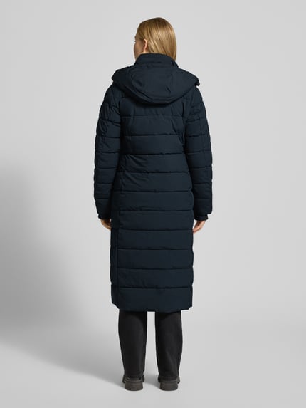 Frauenmodel trägt dunkelblauen Steppmantel mit Sorona® Aura Filling von NAUTGÅRD, wasserabweisend, Rückenansicht Ganzkörperansicht.