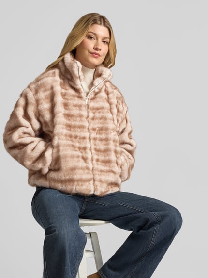 Modelka damska nosi Relaxed Fit Jacke aus Kunstfell mit Stehkragen od zero, jasne paski, zamek błyskawiczny, stójka, Długość tyłu w rozmiarze 36: 54 cm, Szerokość ramion w rozmiarze 36: 47 cm, Szerokość klatki piersiowej w rozmiarze 36: 56 cm, Długość rękawów w rozmiarze 36: 56 cm, tekstura sztucznego futra, widok całej sylwetki z przodu.