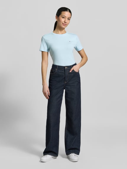 Vrouwenmodel draagt Slim Fit T-Shirt uit zuiver katoen van Tommy Hilfiger in effen lichtblauw met logo-stitching, ronde hals, korte mouw, jersey structuur, vooraanzicht hele lichaam