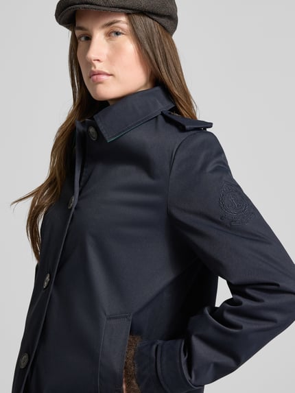 Vrouwenmodel draagt Regular Fit Trenchcoat met Umlegekragen van Lauren Ralph Lauren, donkerblauw, logo detail, lange mouwen, zijzakken, unicolor, schouderkleppen, knoopsluiting, nahaufnahme bovenlichaam.