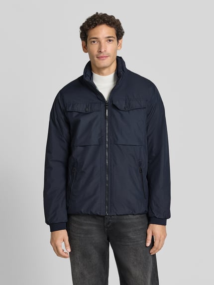 Männermodel trägt Jacke mit Stehkragen und Reißverschlusstaschen von LERROS in Dunkelblau, glatte Textur, Ganzkörperansicht von vorne, Regular Fit, sichtbare Reißverschlüsse und Brusttaschen, Kontext: Rückenlänge 60 cm, Schulterbreite 48 cm, Brustweite 58 cm, Ärmellänge 60 cm.