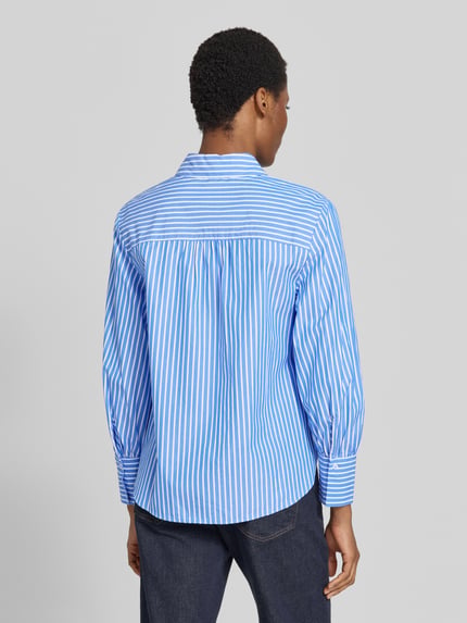 Frauenmodel trägt Regular Fit Hemdbluse aus reiner Baumwolle Modell 'VIC' von Brax mit blau-weißem Streifenmuster, feine Webstruktur, Ganzkörperansicht Rückansicht.