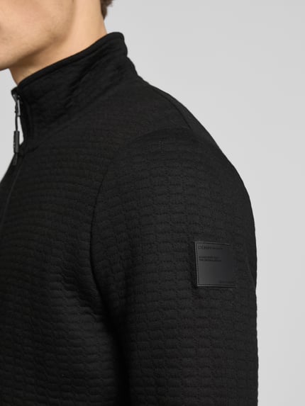 Männermodel trägt Loose Fit Sweatjacke aus Baumwoll-Mix von Tom Tailor Denim in Optik: Unifarben mit Crinkle-Optik und Label-Patch, Nahaufnahme Oberkörper.