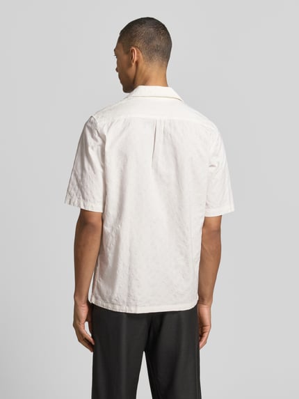 Męski model nosi koszulę casualową Relaxed Fit Freizeithemd mit Strukturmuster Modell 'OSCAR' od Samsøe Samsøe z bawełny, kołnierz z połami, listwa guzikowa, fakturowany wzór, kolor jasny, długość tyłu w rozmiarze M: 73 cm, szerokość ramion w rozmiarze M: 43 cm, długość rękawów w rozmiarze M: 30 cm, całkowity widok z tyłu.