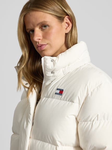 Frauenmodel trägt Regular Fit Steppjacke mit abnehmbarer Kapuze von Tommy Jeans in Weiß, Steppstruktur, Nahaufnahme Oberkörper, Damen Steppjacke von Tommy Jeans.