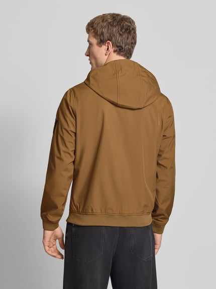 Männermodel trägt braune Softshelljacke mit Reißverschlusstaschen von Jack & Jones, Kapuze, Regular Fit, Rückenansicht, Ganzkörperansicht Rückansicht.