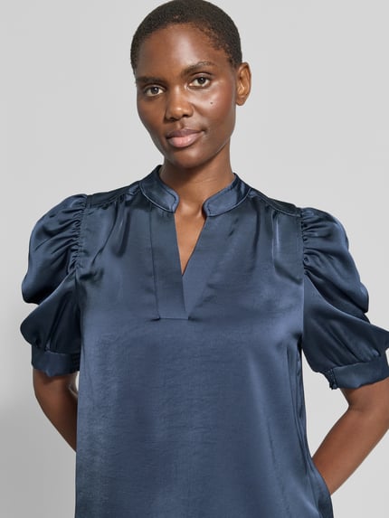 Frauenmodel trägt Regular Fit Bluse aus Satin mit Puffärmeln Modell 'Roella' von Neo Noir, dunkelblau, glatte Textur, Nahaufnahme Oberkörper.