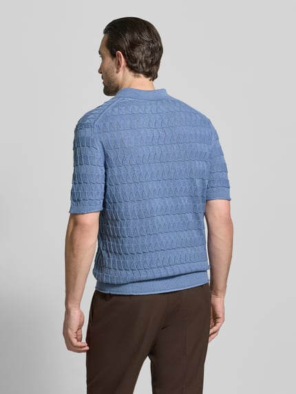 Männermodel trägt Regular Fit Poloshirt mit Strukturmuster von Scotch & Soda in Blau aus reiner Baumwolle, Ganzkörperansicht Rückansicht.