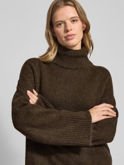Vrouwenmodel draagt Oversized Strickpullover met Rollkragen van Gina Tricot in bruin, grof gebreid, katoenmix, geribde boorden, Nahaufnahme bovenlichaam.