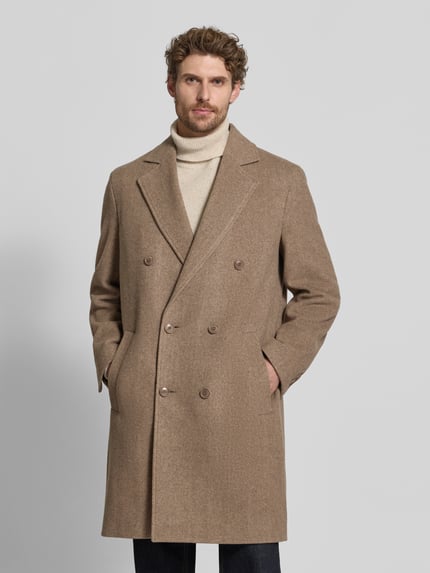 Männermodel trägt Mantel mit Reverskragen und Eingrifftaschen Modell 'NEKOLA' von DRYKORN in Hellbraun, Zweireiher, Ganzkörperansicht von vorne. Baumwoll-Mix, Regular Fit, sichtbare Knopfleiste, strukturierte Textur. Kontext: Rückenlänge 104 cm, Schulterbreite 50 cm, Brustweite 59 cm, Ärmellänge 67 cm.