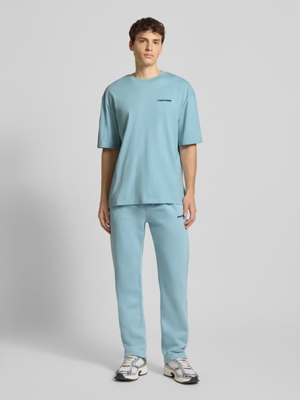 Männermodel trägt Sweathose mit elastischem Bund von Pegador in Hellblau, Baumwoll-Mix, lockerer Schnitt, Ganzkörperansicht von vorne.