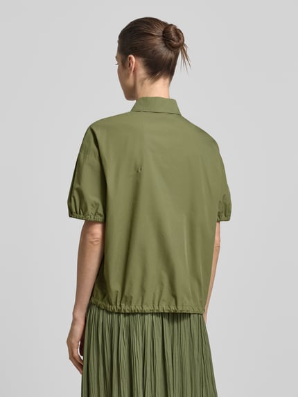 Frauenmodel trägt Regular Fit Bluse mit Polokragen von Marc Cain in Olivgrün, elastische Ärmel, Baumwolle, Rückansicht, Ganzkörperansicht.
