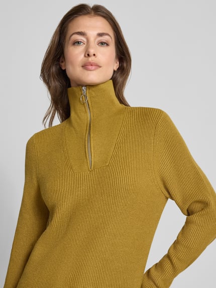 Frauenmodel trägt Regular Fit Strickpullover aus Viskose-Mix von Christian Berg Woman in Senfgelb mit Troyer-Kragen und Rippstruktur, Nahaufnahme Oberkörper. Rückenlänge 61 cm, Ärmellänge 69 cm, Damen Strickpullover, gerippte Abschlüsse.
