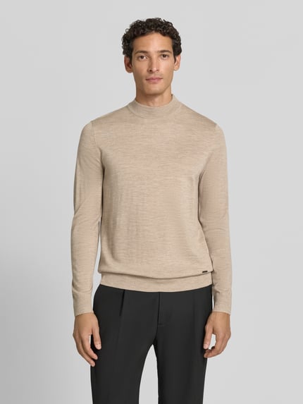 Männermodel trägt Regular fit pullover aus reiner scheerwol Modell 'Davide' von JOOP! HEREN collectie in beige, ganzkörperansicht von vorne.